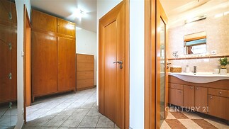 Koupelna s moderním designem, dlažba na podlaze, dřevěné skříňky a velké zrcadlo zvýrazňují světlý a praktický prostor.