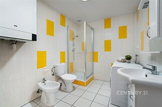 Prostorná koupelna, bílé dlažby, moderní sprchový kout, světlé provedení, vestavěné úložné prostory, rekonstrukce.