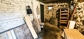 Prázdná sklepní místnost s kamennými zdmi, betonovou podlahou a malým oknem. Potenciál pro skladování nebo rekonstrukci.