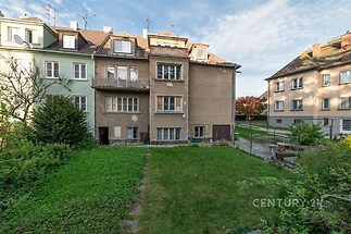 Zahrada s udržovaným trávníkem obklopená rodinnými domy, nabízí klidné prostředí a venkovní prostor pro relaxaci nebo zahradničení.