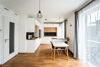 Moderní kuchyň s parketovou podlahou, světlými stěnami a velkými okny. Stylový nábytek a moderní osvětlení dodávají prostoru elegantní atmosféru.