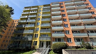 Fasáda bytového domu s barevným exteriérem, prosklené balkony, zrekonstruovaný v moderním stylu, nachází se v klidné lokalitě.