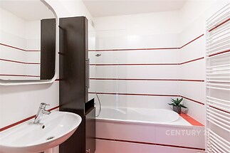 Moderní koupelna s bílými a červenými dlaždicemi, elegantní umyvadlo a sprchový kout, minimalistický design, světlý prostor.