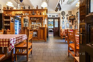 Restaurace s dřevěným nábytkem, dlažbou a vintage dekoracemi. Příjemná atmosféra s prostornými stoly a rustikálním stylem.