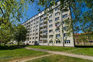 Vícepatrový panelový dům s balkony a zeleným okolím na sídlišti, rekonstruovaný exteriér, klidná lokalita pro rodinné bydlení.