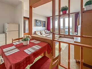 Jídelní kout s dřevěným obložením, velká okna a světlý interiér, navazuje na obývací pokoj.