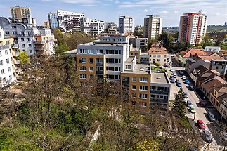 Pohled na bytový dům v rezidenční části města, moderní architektura, světlé fasády, okolní zeleň dodává klidnou atmosféru