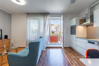 Světlý obývací pokoj s moderní kuchyní, parketová podlaha, velká okna, rekonstruovaný interiér, vstup na balkon poskytuje dostatek denního světla.