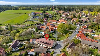 Letecký pohled na klidnou obec obklopenou zelení a lesy, s rodinnými domy a zahradami, ideální pro milovníky přírody a venkovského života.