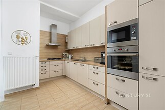 Moderní kuchyň s vestavěnými spotřebiči, světlými skříňkami a dlažbou. Útulná a praktická s moderním designem.