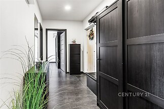 Chodba s moderní dlažbou, velkými černými vestavěnými skříněmi a světlými stěnami, které dodávají prostoru elegantní vzhled.