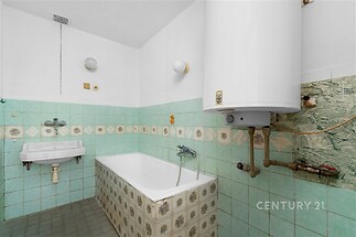 Zrekonstruovaná koupelna s dlažbou, keramickým obkladem a plynovým ohřívačem vody nabízí funkční a útulný prostor.