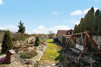 Zahrada s dřevěnými houpačkami, upravenými záhony a okrasnými keři, ideální pro relaxaci, rozlehlý prostor s přírodním prostředím.