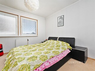 Ložnice s velkými okny, bílými stěnami a komfortní postelí. Světlé prostory s moderním stylem a kobercovou podlahou.