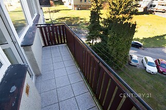 Balkon s dlažbou, dřevěným zábradlím a výhledem na zahradu poskytuje klidné místo k relaxaci. Nachází se zde moderní úpravy vhodné pro relaxaci.