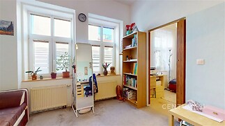 Světlý obývací pokoj s velkými okny, parketová podlaha a vestavěné skříně nabízejí moderní styl a komfort v rekonstruovaném domě.