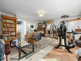 Prostorný obývací pokoj, dlažba, krbová kamna, rustikální styl, světlý interiér, útulný nábytek, dřevěné police, dekorativní stěna.