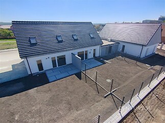 Novostavba rodinného domu s moderní střechou, terasou a prostornou zahradou. Výhled na klidné prostředí.
