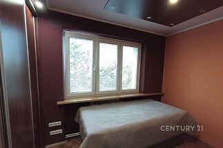 Ložnice s parketovou podlahou a vestavěnými skříněmi, velká okna zajišťují dostatek světla, moderní design interiéru.