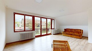 Světlý obývací pokoj s parketovou podlahou, velká okna a moderní styl. Prostorný interiér s výhledem na klidné okolí.
