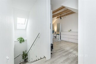 Podkrovní ložnice s dřevěnými trámy, světlá parketová podlaha, moderní vzhled, výklenková vestavěná skříň, světlík pro denní světlo