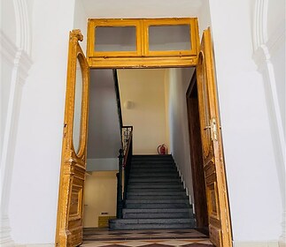 Vstupní hala s dřevěnými dveřmi, parketová podlaha, rekonstruovaný interiér, historické schodiště, vysoké stropy.