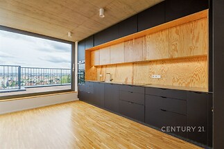 Moderní kuchyň s parketovou podlahou, dřevěnými skříňkami a velkými okny poskytujícími výhled na město, kombinace přírodního dřeva a černého designu
