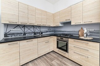 Moderní kuchyň s dřevěnou pracovní deskou, vestavěnými skříněmi a parketovou podlahou, světlé dřevo a elegantní design zajišťují atraktivitu.