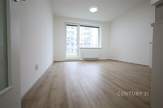 Světlý obývací pokoj s parketovou podlahou, velká okna a moderní styl, ideální pro útulné bydlení v rekonstruovaném bytě