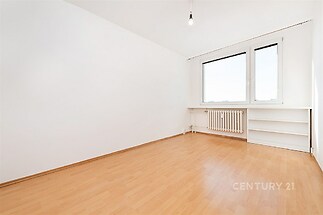 Světlý pokoj s parketovou podlahou a velkými okny, jednoduché bílé zdi, moderní styl a vestavěné police poskytují úložný prostor.