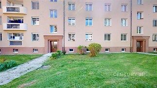 Fasáda bytového domu s novou omítkou, plastová okna a upravený trávník, nachází se v klidné lokalitě.