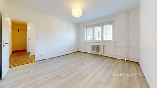 Světlý obývací pokoj s parketovou podlahou a velkými okny, moderní styl, výhled na město, bílá výmalba, prostorný interiér.