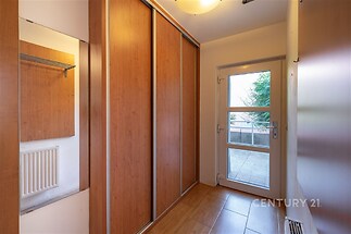 Vstupní chodba s vestavěnými skříněmi a dřevěnými dveřmi, světlá s dlažbou na podlaze a moderním stylovým osvětlením