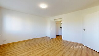 Světlá ložnice s parketovou podlahou, bílé stěny a moderní dveře, prostorný interiér nabízí možnost vestavěných skříní nebo dekorací.