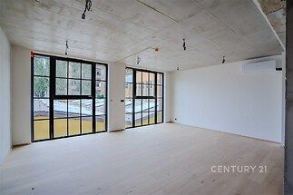 Světlý obývací pokoj s parketovou podlahou, velkými okny a moderním stropním osvětlením. Vynikající rekonstrukce v minimalismu.