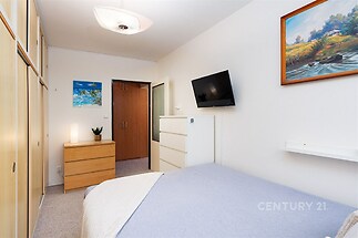 Prostorná ložnice, světlá s vestavěnými skříněmi, moderní dekor, parketová podlaha, minimalistický design, útulný a praktický prostor.