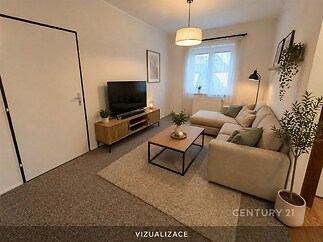 Světlý obývací pokoj s moderním designem, béžový koberec, pohodlná rohová sedačka a velká okna, která zajišťují dostatek přirozeného světla.