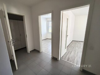 Chodba s dlažbou, vedoucí do světlých pokojů s parketovou podlahou, moderní interiér a dobře využitelný prostor.