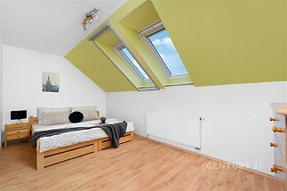 Podkrovní ložnice s parketovou podlahou, velká střešní okna, moderní vzhled, poskytující dostatek světla a prostoru.