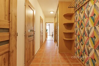 Vstupní chodba s dlažbou, dřevěnými dveřmi a barevným geometrickým vzorem na stěně, nabízí moderní styl a praktické úložné prostory.