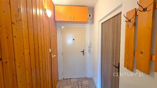 Chodba s dřevěným obložením, dlažbou a vestavěnými úložnými prostory nabízí praktické využití prostoru v rekonstruovaném bytě.