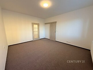 Světlý obývací pokoj s moderními posuvnými dveřmi, světlá kobercová podlaha, neutrální stěny, ideální pro vlastní úpravy.