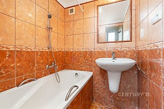 Koupelna s keramickými dlaždicemi nabízí vanu a závěsné umyvadlo, vytvářející útulný prostor se zrcadlem pro komfortní bydlení.