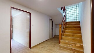 Chodba s dlažbou a dřevěným schodištěm, světlá s moderním designem a prosklenou stěnou, která poskytuje přirozené světlo.