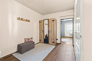 Vstupní hala s dřevěnou vestavěnou skříní, moderní dlažbou a světlými stěnami, poskytuje dostatek úložného prostoru.