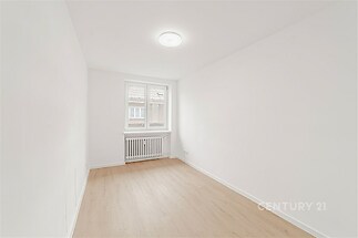 Světlý pokoj s parketovou podlahou, čistě bílé stěny, velké okno s výhledem, moderní design, ideální pro ložnici nebo pracovnu.