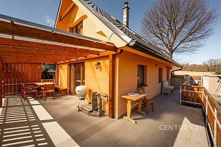 Prostorná terasa se zastřešením, moderní dlažba, dřevěný nábytek, venkovský styl, ideální pro relaxaci a venkovní stolování.