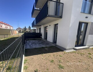 Terasa s moderní dlažbou a kovovým zábradlím, součást novostavby. Nabízí prostor pro posezení, přímý přístup do zahrady, ideální pro relaxaci.