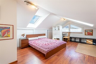 Podkrovní ložnice s dřevěnou podlahou, moderní vestavěné skříně, světlé díky střešním oknům, útulný a vzdušný prostor.