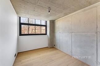 Ložnice s parketovou podlahou, betonovými stěnami a velkými okny, moderní styl s minimalistickým osvětlením